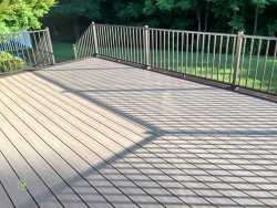 Light gray composite deck with clean, straight board layout and bronze aluminum railing, overlooking a green backyard—professionally built by an experienced deck contractor near me in Charlotte, NC.