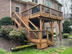 Elevated wood deck with stairs and black metal railing attached to brick home, built by a trusted deck contractor near me in Charlotte, NC