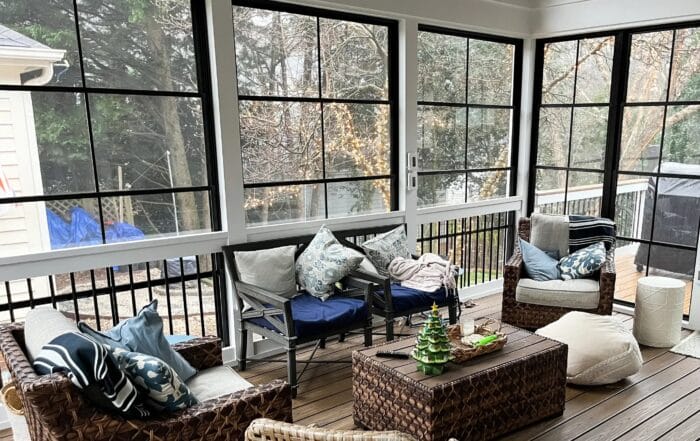 Screened porch with a vaulted ceiling, wood flooring, and comfortable outdoor furniture, providing a cozy outdoor living space.